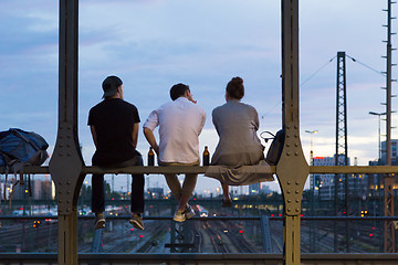Image showing Young friends sitting on urban railway bridge, Munich, Germany.