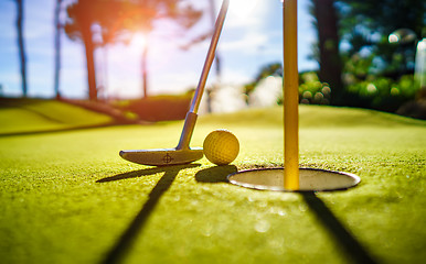 Image showing Mini Golf yellow ball with a bat near the hole at sunset