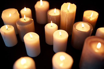 Image showing candles burning in darkness over black background