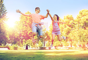 Image showing happy teenage couple jumping at summer park