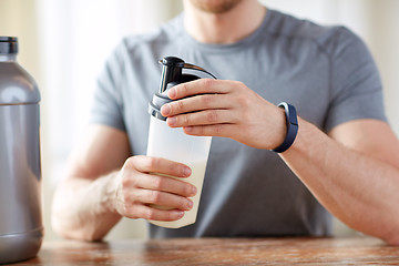 Image showing close up of man with protein shake bottle and jar