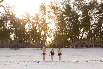 Image showing Group of Senior Friends Enjoying Beautiful Sunset Walk on the Beach.