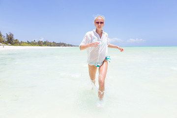 Image showing Young active woman having fun running and splashing in shellow sea water.