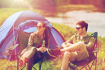 Image showing happy couple drinking beer at campsite tent