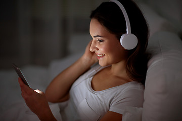 Image showing woman with smartphone and headphones in bed