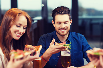 Image showing friends eating pizza with beer at restaurant