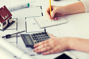 Image showing close up of hand on blueprint writing to notebook