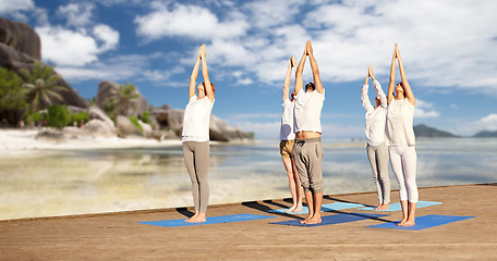 Image showing group of people making yoga exercises over beach