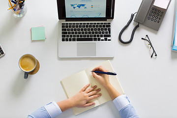 Image showing businesswoman hands writing to notebook at office