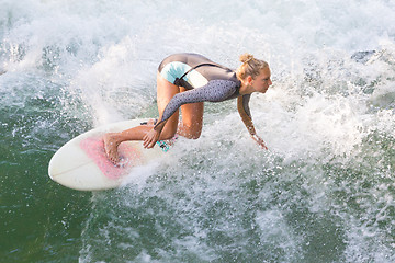 Image showing Atractive sporty girl surfing on famous artificial river wave in Englischer garten, Munich, Germany.