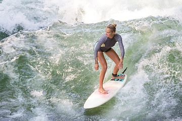 Image showing Atractive sporty girl surfing on famous artificial river wave in Englischer garten, Munich, Germany.