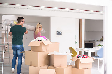 Image showing couple carrying a carpet moving in to new home