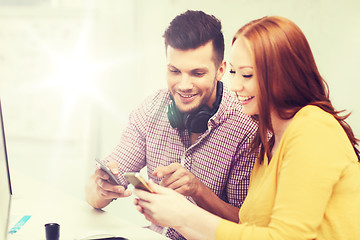 Image showing smiling creative team with smartphones at office