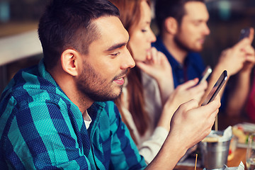 Image showing friends with smartphones dining at restaurant