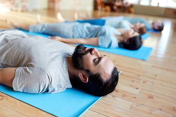 Image showing man with group of people doing yoga at studio