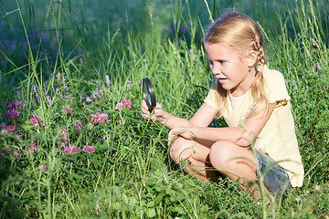 Image showing Happy little girl exploring nature with magnifying glass 