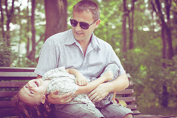 Image showing Father and son playing at the park on bench at the day time.