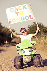 Image showing Happy little boy playing on road at the day time. He driving on 