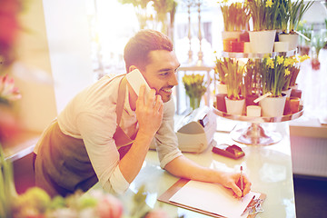 Image showing man with smartphone making notes at flower shop