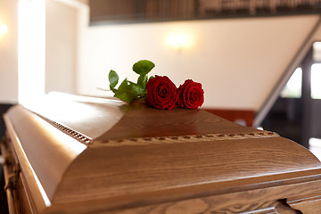 Image showing red rose flowers on wooden coffin in church