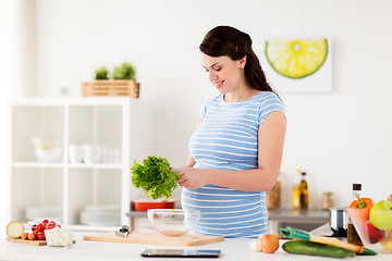 Image showing pregnant woman cooking vegetable salad at home