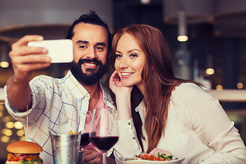 Image showing couple taking selfie by smartphone at restaurant