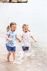 Image showing Children on the sea beach. Twins going along sea water.