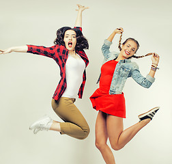 Image showing two pretty brunette and blonde teenage girl friends jumping happy smiling on white background, lifestyle people concept 