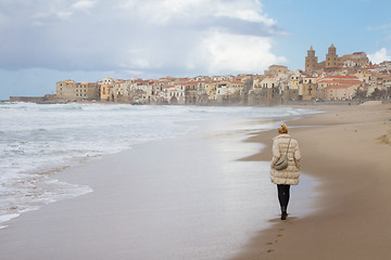 Image showing Solitary woman walking the beach of Cefalu in winter time, Sicily, south Italy.