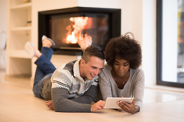 Image showing multiethnic couple using tablet computer on the floor