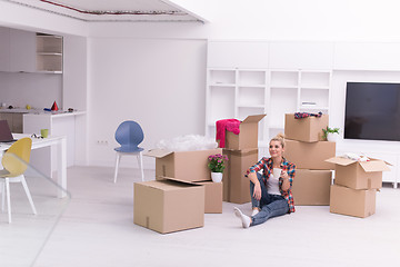 Image showing woman with many cardboard boxes sitting on floor