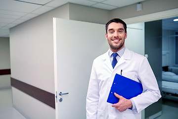 Image showing happy doctor with clipboard at hospital corridor