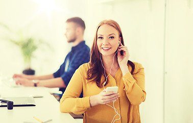 Image showing woman with earphones and smartphone at office