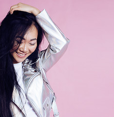 Image showing young pretty smiling asian korean girl wearing modern fashion clothers on pink background, lifestyle people concept 