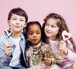 Image showing lifestyle people concept: diverse nation children playing together, caucasian boy with african little girl holding candy happy smiling 