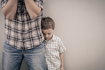 Image showing sad son hugging his dad near wall