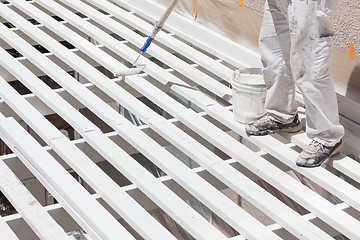 Image showing Professional Painter Rolling White Paint Onto The Top of A Home 