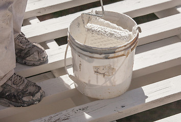 Image showing Professional Painter Rolling White Paint Onto The Top of A Home 