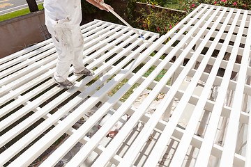 Image showing Professional Painter Rolling White Paint Onto The Top of A Home 