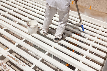 Image showing Professional Painter Rolling White Paint Onto The Top of A Home 