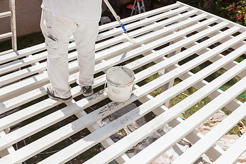 Image showing Professional Painter Rolling White Paint Onto The Top of A Home 