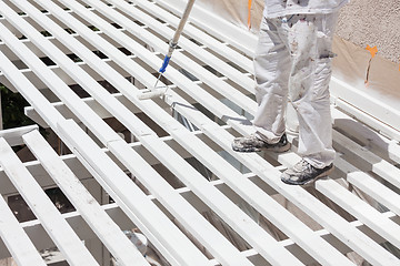 Image showing Professional Painter Rolling White Paint Onto The Top of A Home 