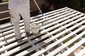 Image showing Professional Painter Rolling White Paint Onto The Top of A Home 