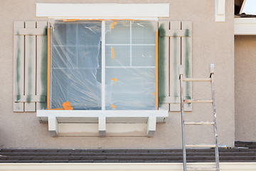 Image showing Construction Ladder Leaning Up Against A House Being Painted