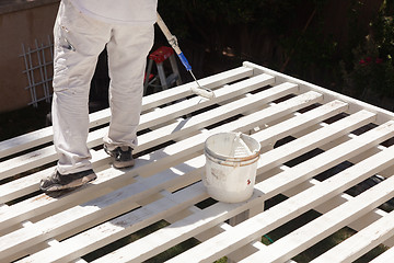 Image showing Professional Painter Rolling White Paint Onto The Top of A Home 