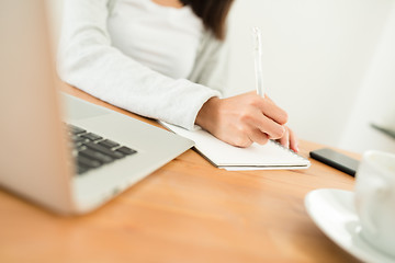 Image showing Woman writing on the note book on her desk