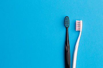 Image showing Black, pink toothbrushes on blue