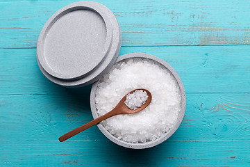Image showing Sea salt in an stone bowl with small wooden spoon on a blue wooden table