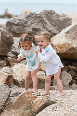 Image showing Children on the sea beach. Twins standing against stones and sea water.