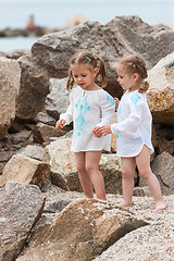 Image showing Children on the sea beach. Twins standing against stones and sea water.